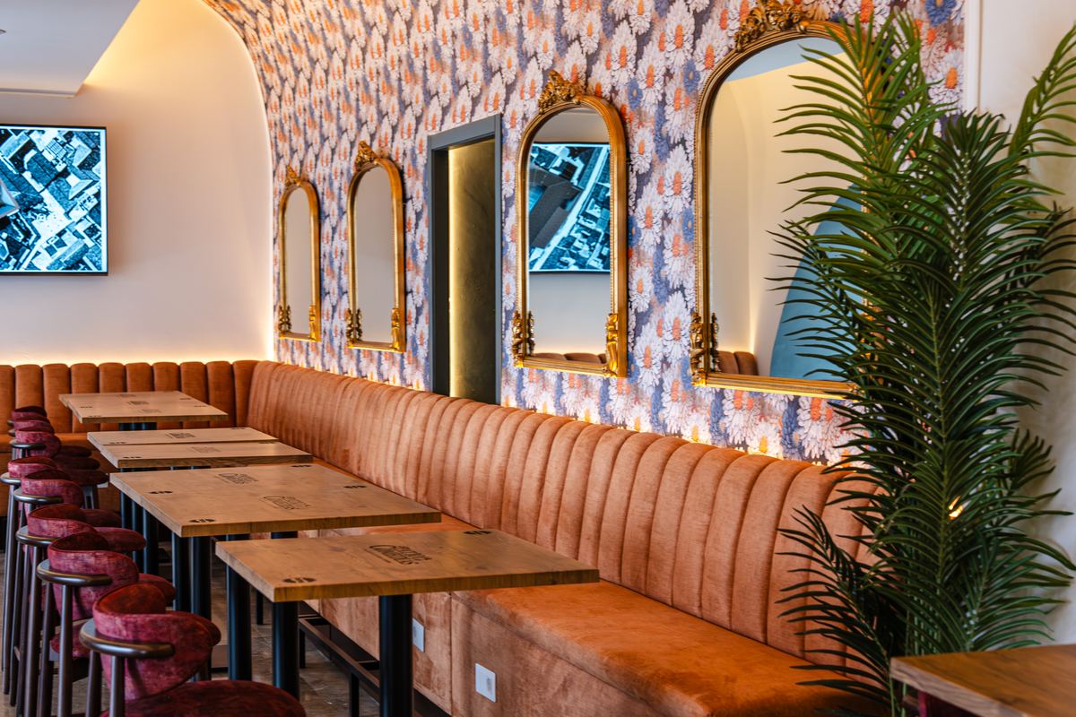 El salón de la taberna, con papel pintado de flores, banco corrido color terracota y espejos dorados