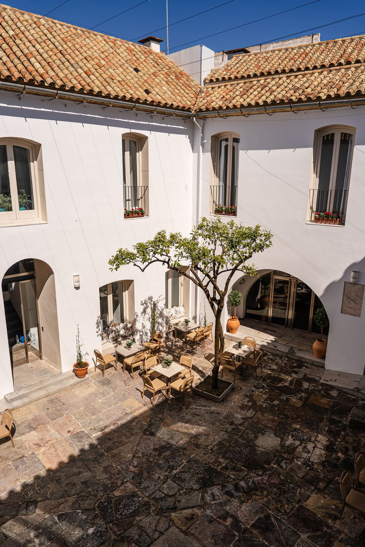 El patio entero desde la planta alta, con el naranjo y las mesas de la taberna