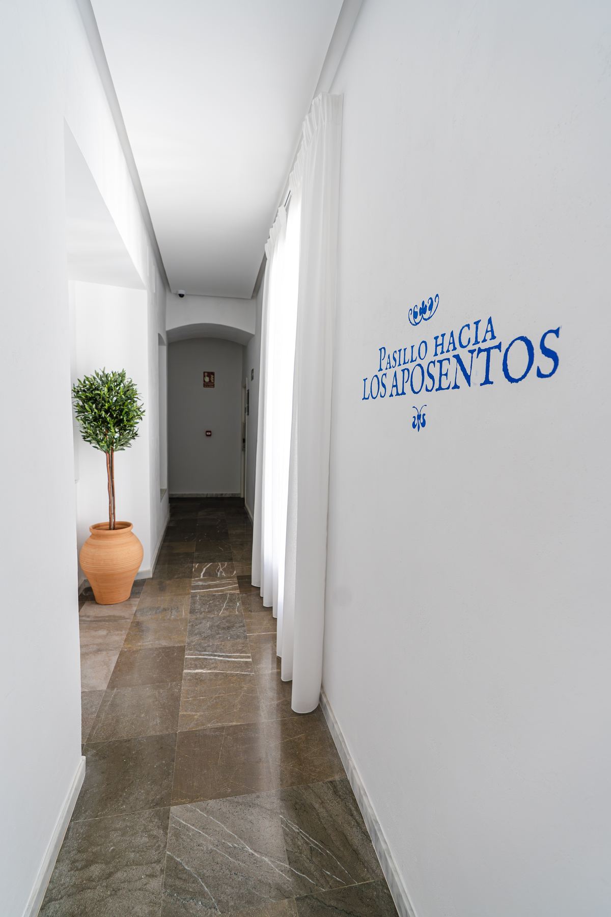 Pasillo blanco con el rótulo «Pasillo hacia los aposentos»